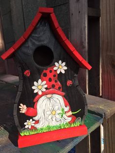 a birdhouse with a gnome and flowers painted on it