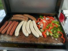 hot dogs and vegetables cooking on an outdoor grill