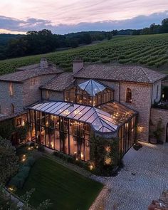 an aerial view of a large house in the middle of a field with lights on it