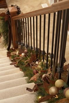 christmas garland on the bannister railing with lights and ornaments hanging from it's handrail