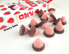 small pink and brown candy candies next to a box of strawberry milk chocolates