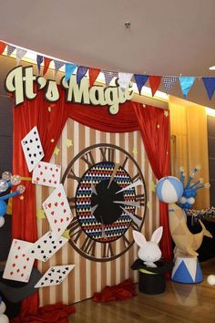 a large clock surrounded by balloons and streamers in front of a red curtain with bunting