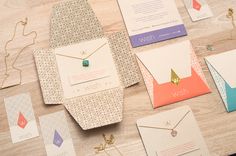 several different types of cards and envelopes on a table with gold chains, necklaces, and other items