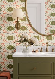 a bathroom vanity with an oval mirror above it and flowers on the counter in front of it