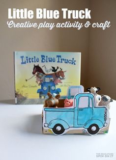 a little blue truck with animals in it and a book on the table next to it