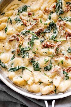 a pot filled with pasta and spinach covered in cheese