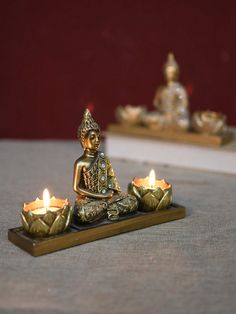 a small buddha statue sitting on top of a table next to some lit up candles