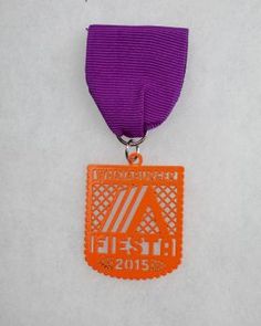 an orange and purple medal is hanging on a white wall