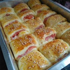 ham and cheese rolls in a baking pan ready to be baked with sesame seed sprinkles