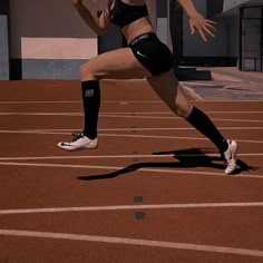 a woman is running on a track with her leg in the air and one hand out