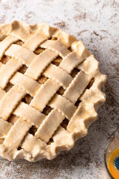 an uncooked pie sitting on top of a table next to a bowl of orange juice