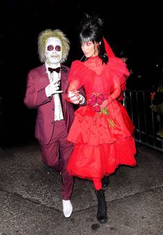 two people dressed up in costumes walking down the street