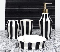 three black and white striped vases sitting on top of a counter next to a soap dispenser