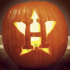 a carved pumpkin with the letter h in it's center and an arrow on top