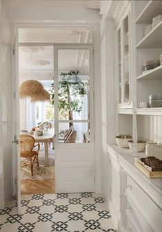 an open door leading to a dining room with white walls and floor tiles on the floor