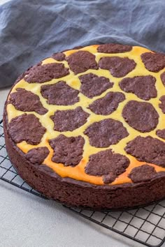 a chocolate cake with yellow icing and hearts on top sitting on a cooling rack