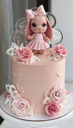 a pink cake decorated with flowers and a teddy bear