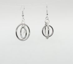 These playful and flirty spinner earrings defy gravity with their steel hoops and crystal bead accent. The inner part spins for a cool and distinctive effect. The metal is hypoallergenic stainless steel that won't tarnish easily. The largest circle measures about an inch and a half in diameter. They're lightweight and perfect for fidgeting, just like me! Modern Twist Hoop Earrings In Metal, Modern Internally Threaded Adjustable Earrings, Modern Internally Threaded Silver Earrings, Internally Threaded Metal Hoop Earrings For Gift, Pierced Stainless Steel Hoop Earrings, Modern Twist Round Metal Earrings, Modern Twist Hoop Metal Jewelry, Modern Twist Metal Hoop Earrings As Gift, Silver Spiral Hoop Earrings In Metal