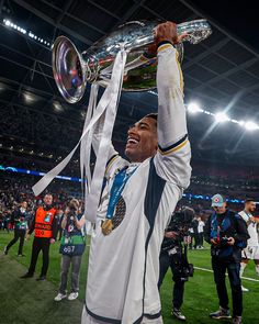 a man holding up a trophy on top of a field