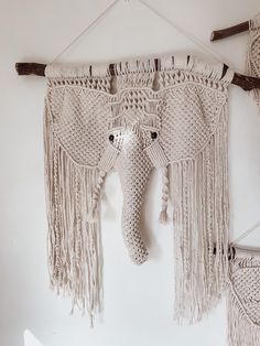 an elephant's head hanging on the wall with macrame beads and tassels