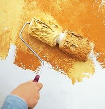 a person is using a paint roller to paint a wall with orange and yellow colors