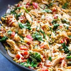 a pan filled with pasta and vegetables on top of a blue tablecloth covered surface