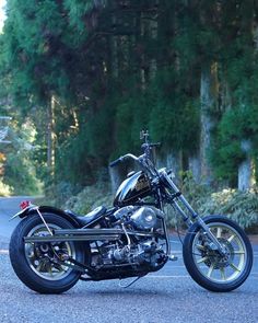 a black motorcycle parked on the side of a road next to some trees and bushes