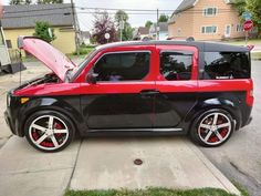 a small black and red car parked on the side of a street with its hood open