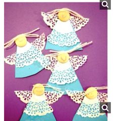 paper angel ornaments are arranged in the shape of angels on a purple background with white doily