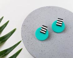 a pair of earrings sitting on top of a table next to some leaves and a plant