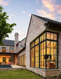 a large brick house with lots of windows on the front and side of it at dusk