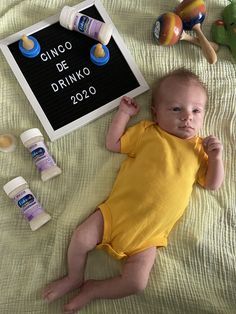 a baby laying on top of a bed next to some bottles and other items in front of him