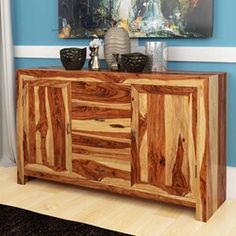 a wooden sideboard with two vases on top and a painting above the cabinet