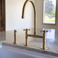 a kitchen sink with two faucets on the side and a window in the background