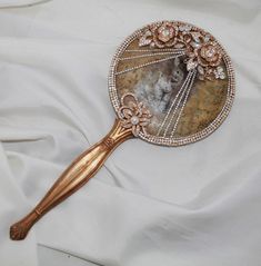 a close up of a hair brush on a white cloth with gold trimmings