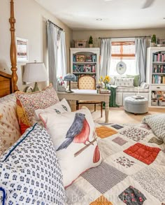 a bedroom with quilts and pillows on the bedspread in front of a window