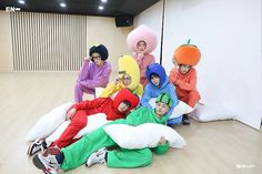 a group of people dressed in costumes posing for a photo on the floor with pillows