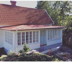 a white house with a red roof and some trees in the backround area