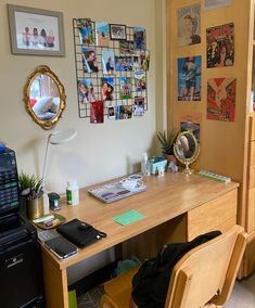 a wooden desk topped with a laptop computer next to a window covered in pictures and magnets