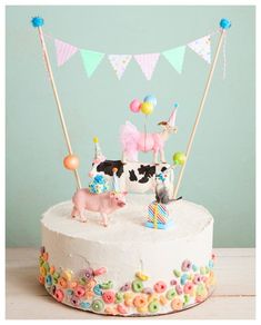 a birthday cake decorated with farm animals and balloons