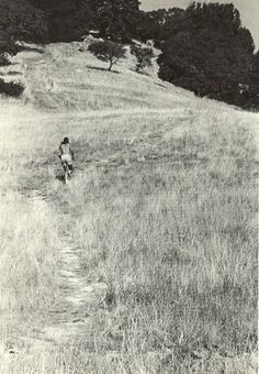 an old black and white photo of a person walking up a hill