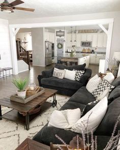 a living room filled with black couches and white pillows