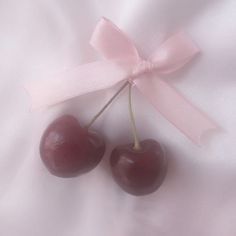 two cherries tied together with a pink ribbon