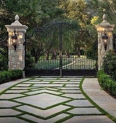 an entrance to a home with stone walkways and gated in area surrounded by greenery