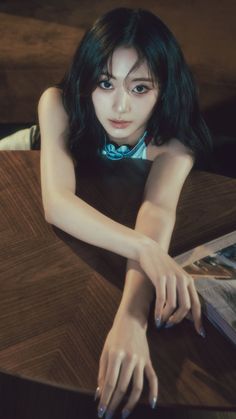 a woman sitting at a table with her hand on top of the table and magazine in front of her