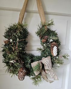 a wreath hanging on the front door decorated with pine cones, evergreen and snowflakes