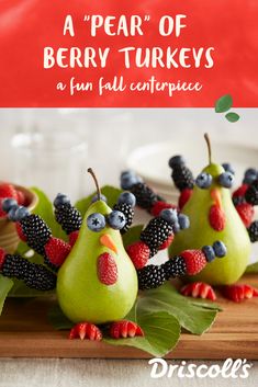 pears with berries and blackberries in them on a cutting board next to some leaves