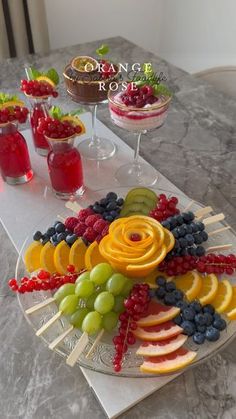 an assortment of fruit on a platter next to glasses of wine and cranberry sauce