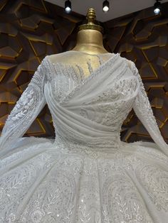 a white wedding dress is on display in a room with gold and black wallpaper