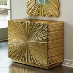 a golden cabinet with a mirror above it and a painting on the wall behind it